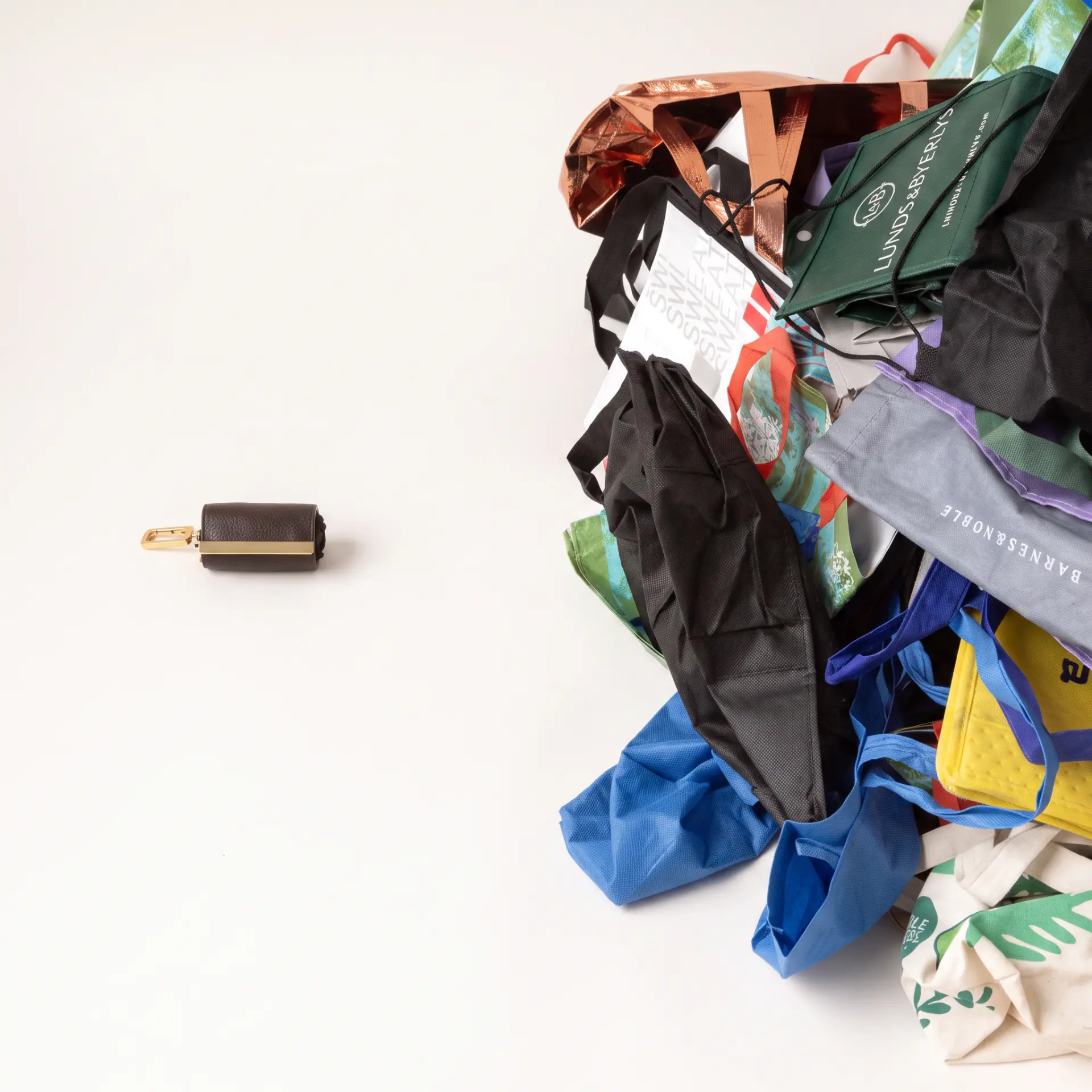 One folded cliptote next to a pile of single-use tote bags